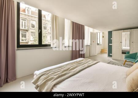 A cozy and contemporary bedroom featuring large windows, sheer curtains, and minimalistic furniture. Stock Photo