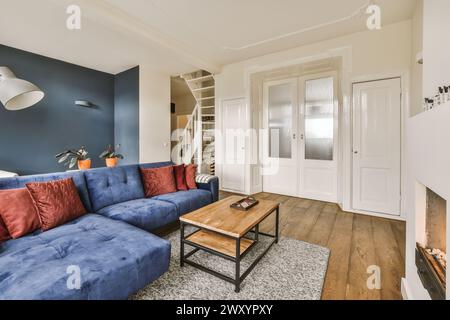 Spacious living room featuring a plush blue sectional sofa, red cushions, a coffee table, and a cozy fireplace. Stock Photo
