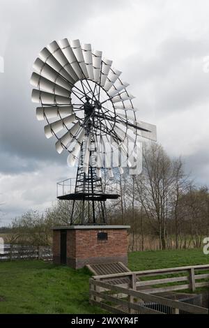 American windmill on a dike in the Netherlands for regulating the waterlevel in a polder Stock Photo