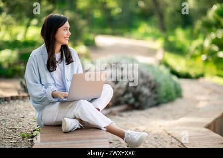 Woman using laptop outdoors at public park Stock Photo