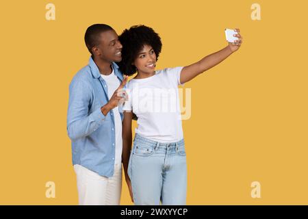 Couple taking selfie with smartphone on yellow Stock Photo