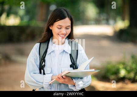 Young woman reading outdoors at public park with smile Stock Photo