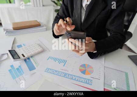 business accountant woman use calculator to calculate company's profit percentage and look at data on her mobile Stock Photo