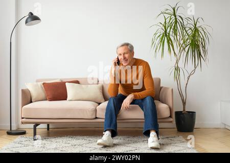 Man sitting on couch talking on phone Stock Photo