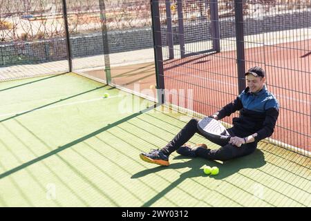 Portrait of positive young man with racket and padel ball on tennis court Stock Photo