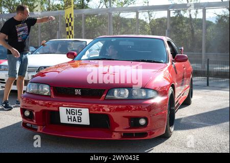 Front view of a red ninth-generation Nissan Skyline GT-R33 at a Japanese sports car meet. Stock Photo