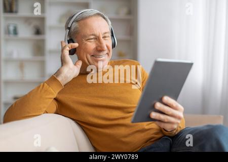 Happy senior man with headphones using tablet Stock Photo
