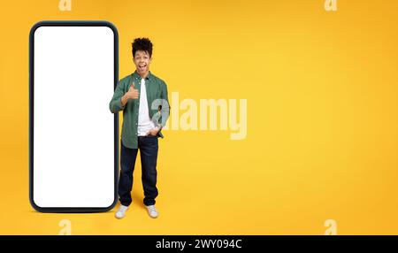 Happy young african american man presenting a smartphone with mockup Stock Photo