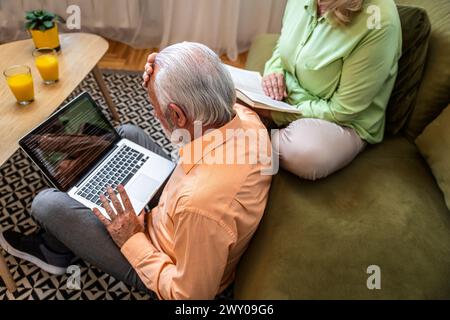 Senior couple at home reading bad news on laptop. Stock Photo