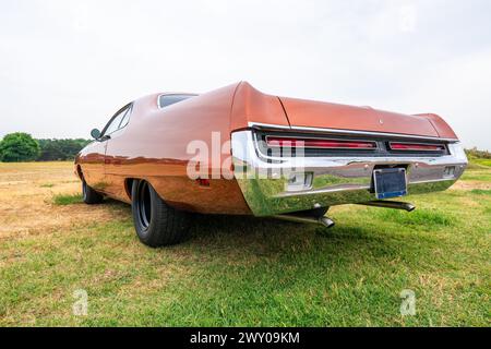 Side view of a classic american car from the fifties. Low angle view showing red paint and chrome fender and grill. Stock Photo