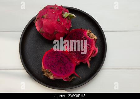 A Dragon fruit on black plate with white background Stock Photo