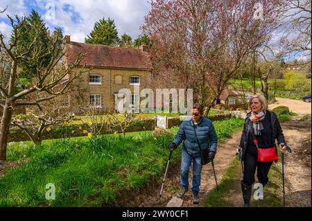 Two middle-aged women walking along a gravel road past a The Mill House in early spring in Nutbourne near Pulborough in rural West Sussex, England. Stock Photo