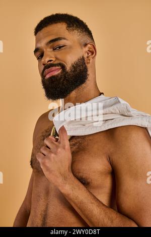 A bearded man stands with a towel wrapped around his neck, likely at a barber shop preparing for a haircut or shave. Stock Photo
