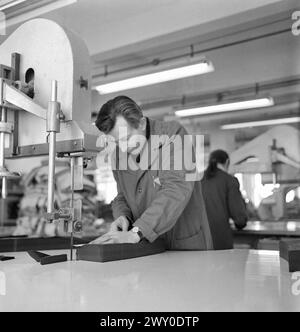 Socialist Republic of Romania in the 1970s. Worker using a fabric cutting machine in a state-owned factory. Stock Photo