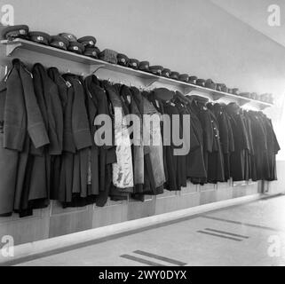 Socialist Republic of Romania in the 1970s. Soviet-type greatcoats and visor hats of  high rank military officials hanging on a coat rack in a barrack. Stock Photo