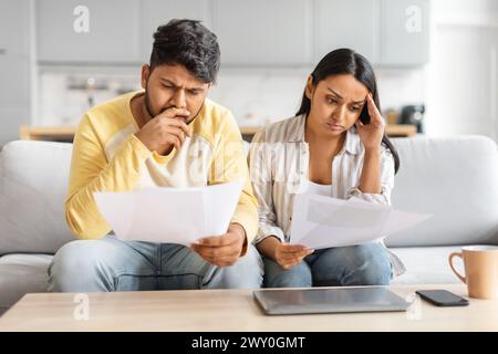 Indian Man and Woman Sitting on Couch At Home With Paperwork Stock Photo