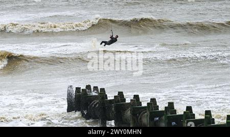 Worthing UK 3rd April 2024 -  Kite surfers make the most of the strong winds near an outfall pipe at Lancing near Worthing during windy weather along the South Coast today : Credit Simon Dack / Alamy Live News Stock Photo