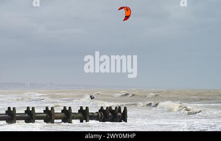 Worthing UK 3rd April 2024 -  Kite surfers make the most of the strong winds near an outfall pipe at Lancing near Worthing during windy weather along the South Coast today : Credit Simon Dack / Alamy Live News Stock Photo