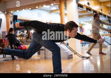 Side view of the effort face and throwing technique of the bowling ball. on a young player dressed in black Stock Photo