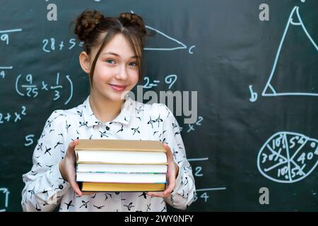 Girl schoolgirl with four books in her hands, concept of school life preparing exams. Stock Photo