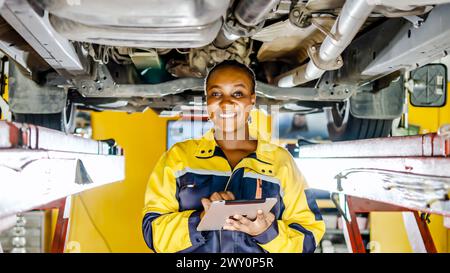 Woman seated under a vehicle in a garage Stock Photo