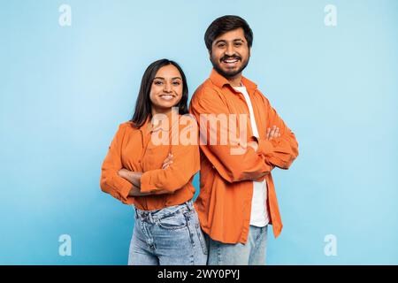 Two people posing confidently together on blue Stock Photo