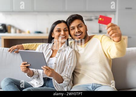 Indian Man and Woman Holding Tablet and Credit Card on Couch Stock Photo