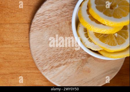 lemon slices in a round white dish on a round wooden cutting board Stock Photo