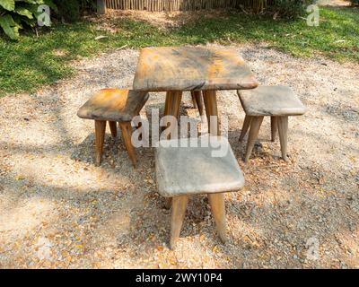 The small wooden chair and table set for relaxing time on the stone floor near the tropical  garden, front view for the copy space. Stock Photo