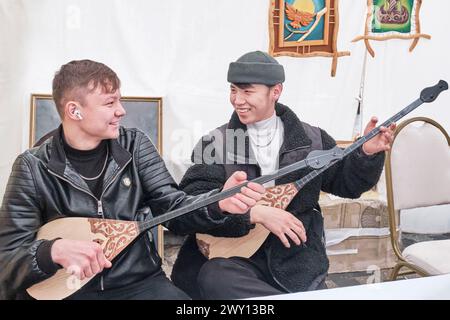Two teens playing kazakh folk musical instruments,dombras. Spring festival Nowruz. Almaty,Kazakhstan Stock Photo
