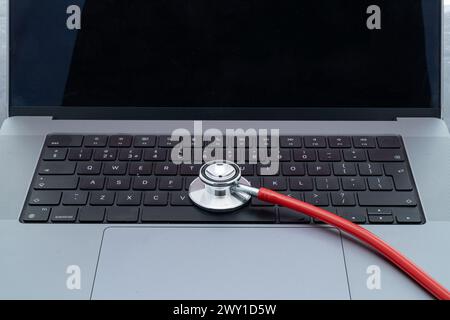 A modern stethoscope resting on a laptop keyboard Stock Photo