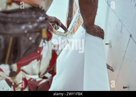 Man construction worker cutting polystyrene foam heat insulation with hand saw, closeup detail Stock Photo