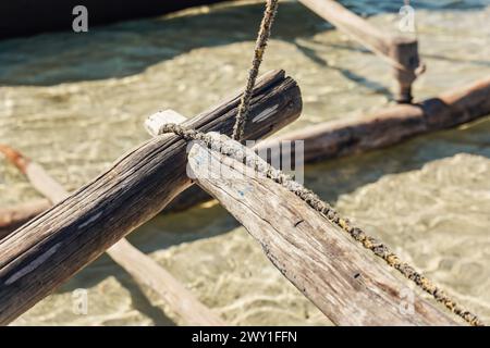 Simple natural rope tied around wooden part of pirogue - African simple fishing boat, closeup detail Stock Photo