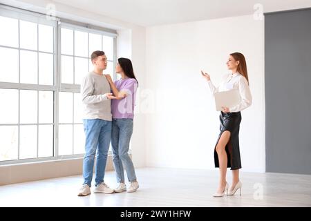Female realtor with laptop showing young couple new house Stock Photo