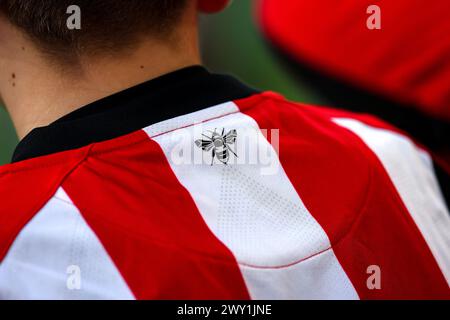 3rd April 2024; Gtech Community Stadium, Brentford, London, England; Premier League Football, Brentford versus Brighton and Hove Albion; Young Brentford fan observing Brentford players warming up while wearing the 2023/24 home shirt Stock Photo