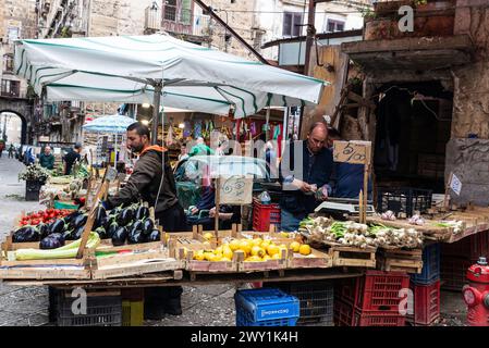 Palermo, Italy - May 13, 2023: Vendors at a fruit and vegetable shop, one of them counting money, in Ballaro Market, street food market in Palermo, Si Stock Photo