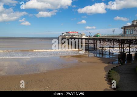 Cromer Pier, Norfolk. Cromer Pier on a sunny day with a few white clouds. A coloured image of the underside of the Pier. The tide is going out. Stock Photo