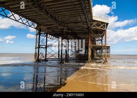 Cromer Pier, Norfolk. Cromer Pier on a sunny day with a few white clouds. A coloured image of the underside of the Pier. The tide is going out. Stock Photo