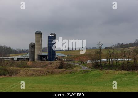 Agricultural landscape with barn and silos on a hillside under cloudy skies in rural Virginia, USA Stock Photo