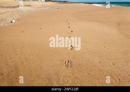 isolated footsteps trail into the distance on this sandy Quarteira, Portugal beach. Stock Photo