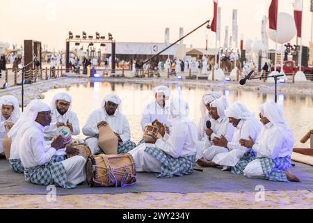 A Qatari band with traditional clothes playing a musical instrument from the Qatari heritage, celebrating Qatar National Day Stock Photo