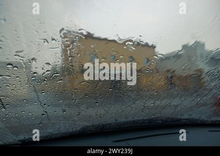 Drizzle on the windshield in the evening. blurred scenery with rainy day. View from car seat at Doha Qatar Stock Photo