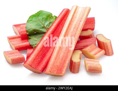 Red rhubarb stems' cuts over rhubarb leaves isolated on white background. Stock Photo
