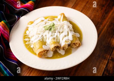 Green enchiladas. Typical Mexican dish made with a folded or rolled corn tortilla filled with shredded chicken and covered with spicy green sauce, cre Stock Photo