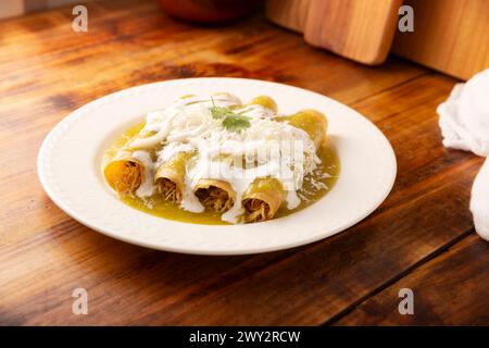 Green enchiladas. Typical Mexican dish made with a folded or rolled corn tortilla filled with shredded chicken and covered with spicy green sauce, cre Stock Photo