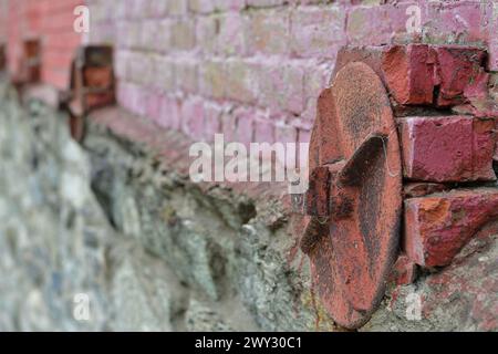 Old style brick wall retainer. Old brick wall reinforced with round metal plates. Stock Photo