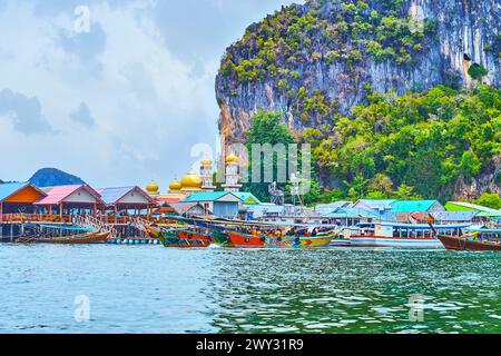 The boat trip along the shore of Ko Panyi (Koh Panyee) floating village with a view of the shipyards, stilt houses, wooden piers and golden domes of l Stock Photo