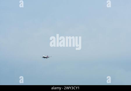 White twin engine commercial jet airliner with red vertical stabilizer flying in clear blue sky in South Korea Stock Photo