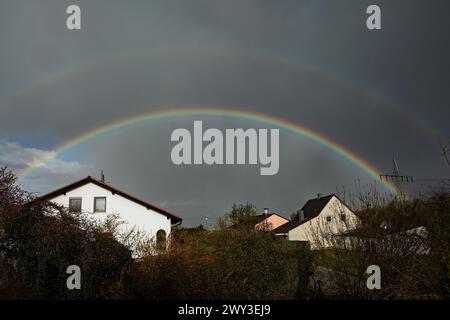 Rainbow over houses and electricity pylons against a blue sky Stock Photo