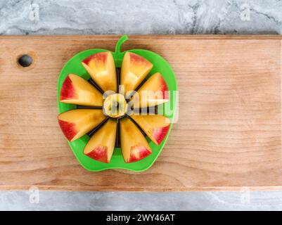 An apple on a cutting board is cut into slices using a special slicer in the shape of an apple Stock Photo